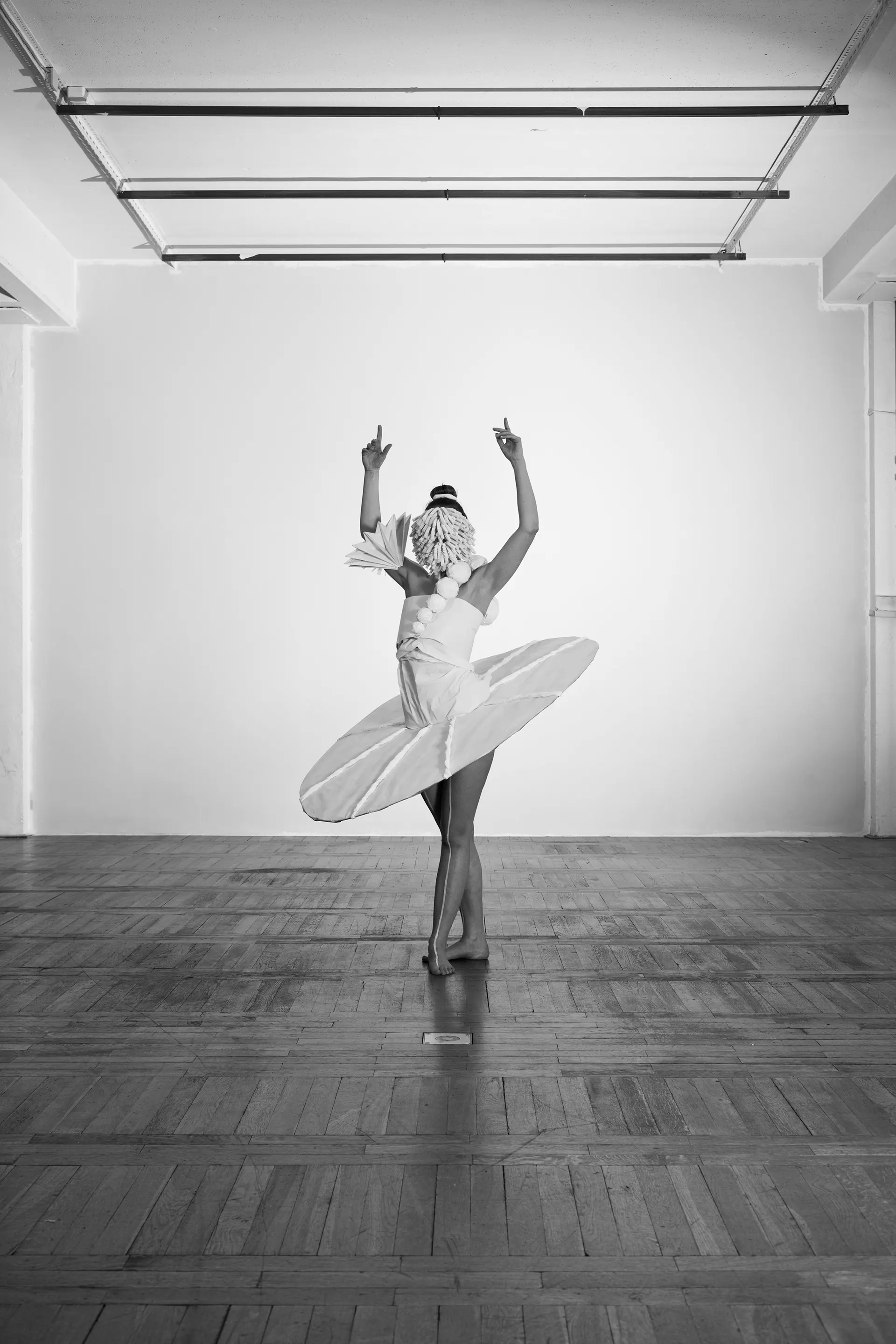 Dancer in the paper costume with a disc-shaped skirt in an empty hall, black and white