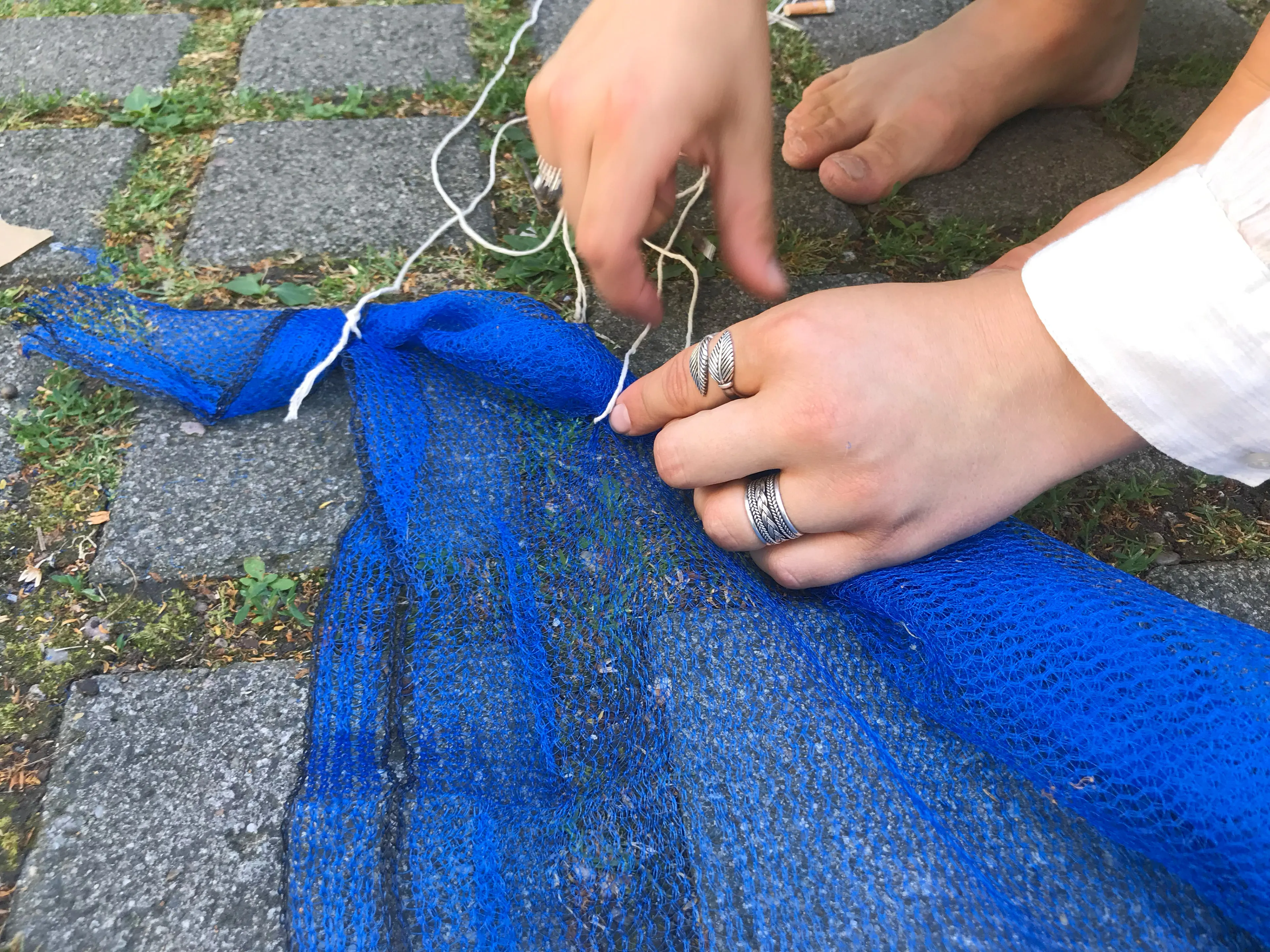 Hands knotting a blue net into one element of the wave