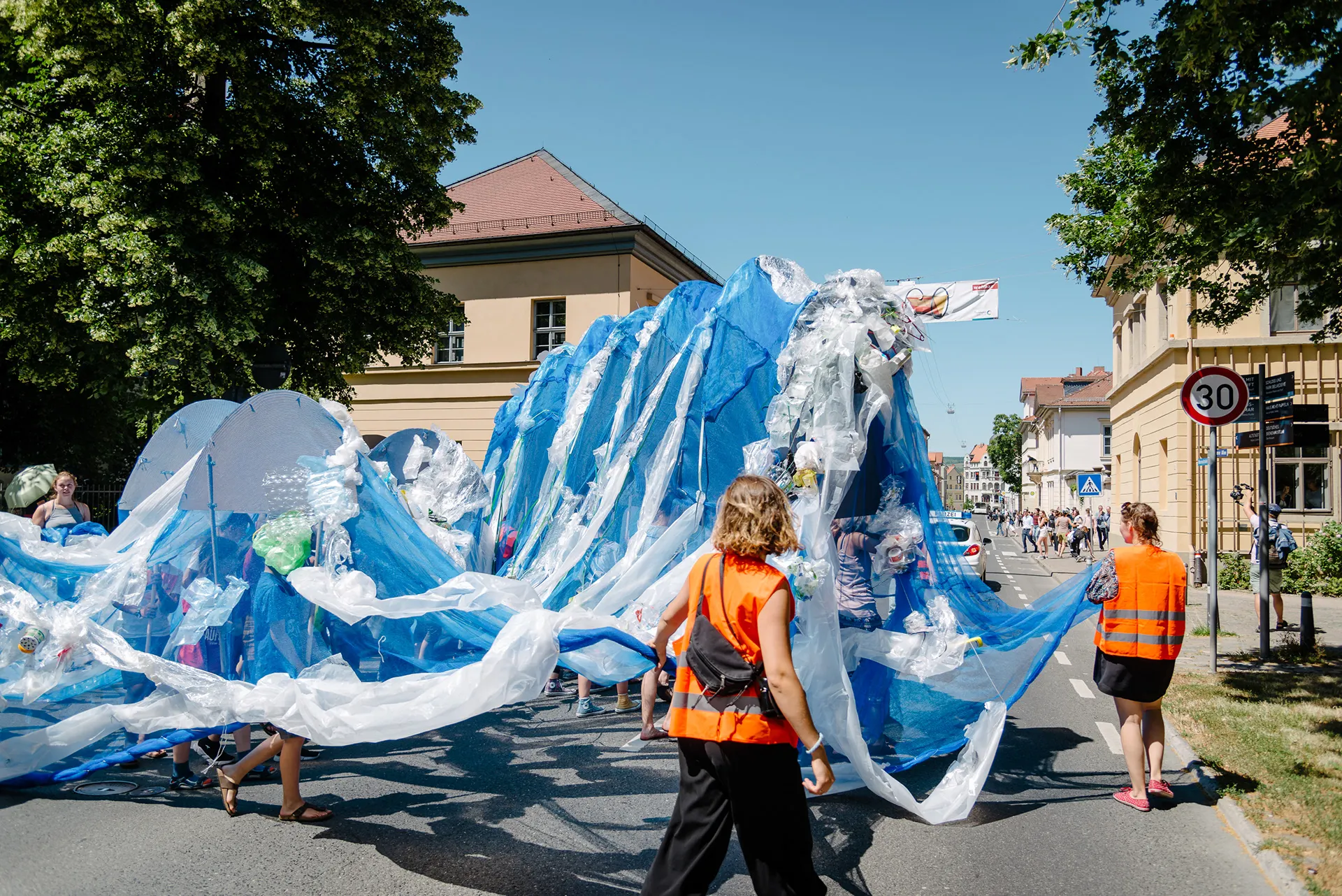 The wave of plastic sheeting in motion on a sunny street, accompanied by stewards